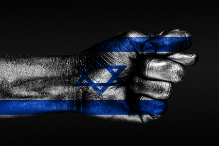A hand with a painted Israel flag shows a fig, a sign of aggression, disagreement, a dispute on a dark background. Horizontal frameの写真素材