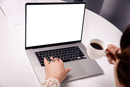 close-up of female hands on a laptop with a white screen for an inscriptionの写真素材