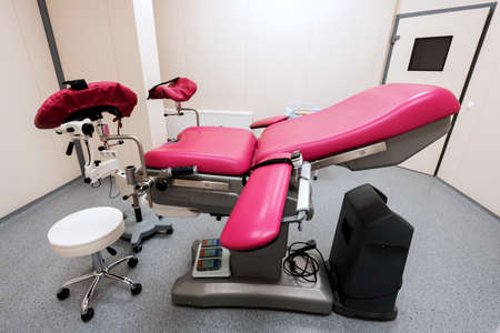 modern, multifunctional pink gynecological chair in the center of the roomの写真素材