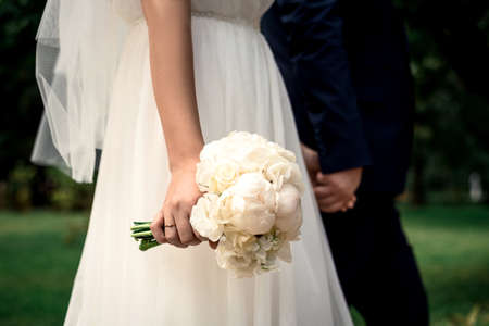 hugging hands of newlyweds with rings and flowers close-upの写真素材