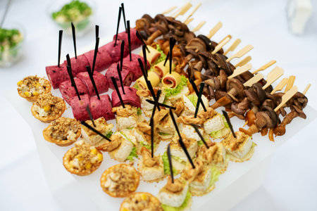 Beautifully decorated catering banquet table with different food snacks and appetizers with sandwich, caviar, fresh fruits on corporate party event or wedding celebrationの写真素材