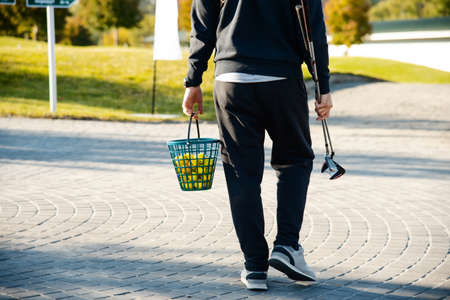 Golfer carries clubs and a bucket of ballsの写真素材
