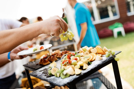 close-up of a man's hand takes grapes from a plate of fruitの写真素材