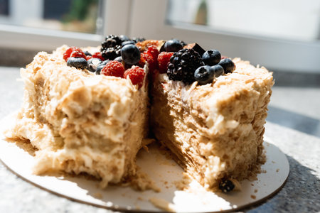 Savoyardi berry cake garnished with blackberries,blueberries and fresh figs on a wooden stand with hydrangea flowers on wooden table.Close up of cake in rustic style.の写真素材