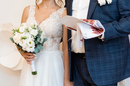 The bride and groom stand on an embroidered towel with the inscription for luck and fate in Ukrainian during a church wedding.の写真素材