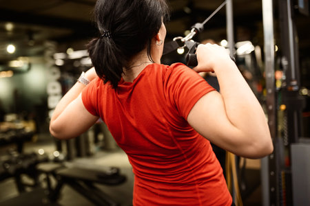 Sporty woman doing thrust of upper block to chest. Girl doing workout exercise with thrust of Pulldownの写真素材