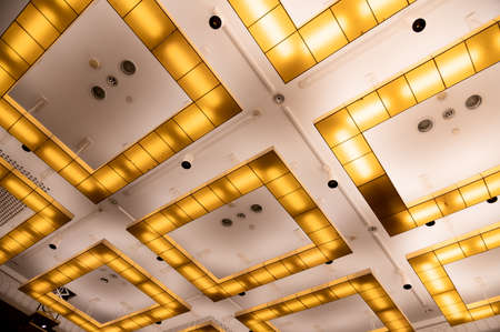 conceptual chandeliers, square yellow lamps on white ceiling
