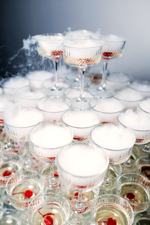 many glasses of champagne with cherries stand on top of each other