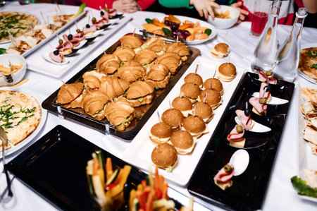 a lot of different food on the buffet, burgers, canapes, croissants and vegetablesの写真素材