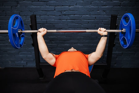 Brutal athletic man pumping up muscles on bench press