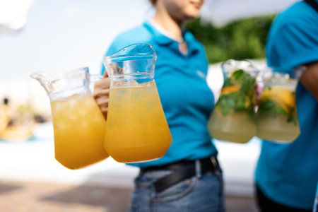 girl waiter carries four carafes of lemonade
