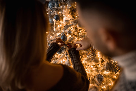 close-up of the hands of a man and a woman decorate the Christmas tree with ballsの写真素材
