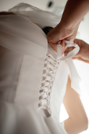 Close up of Hands Doing Final Buttoning of Bride's Wedding Dressの写真素材