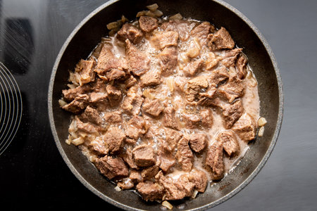 close-up beautiful large pieces of fried meat with onions in a panの写真素材
