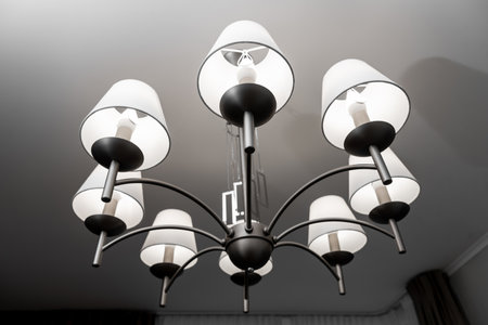 A round chandelier of several lamps against a light ceiling, full frame, bottom viewの写真素材
