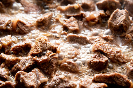 close-up beautiful large pieces of fried meat with onions in a panの写真素材