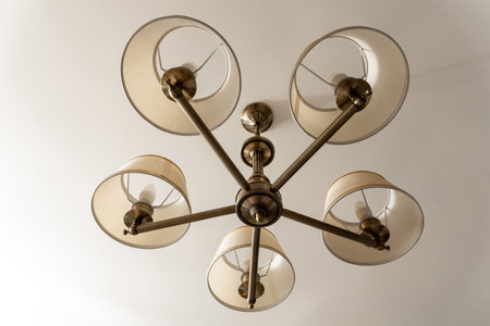 A round chandelier of several lamps against a light ceiling, full frame, bottom viewの写真素材