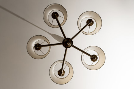 A round chandelier of several lamps against a light ceiling, full frame, bottom view