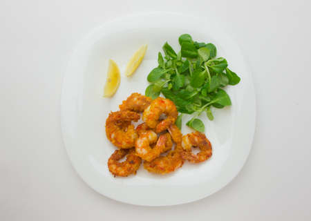 Fried shrimps on a plate. Prawns fried in breading on a white plate with salad and lemon.の写真素材