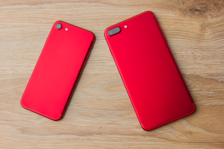 Two red phones on the desk. Smartphones of red color on a wooden table.の写真素材