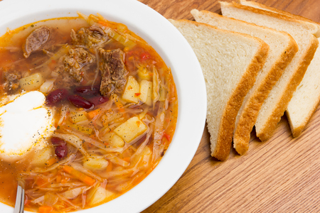 Borsch, a ready-made dish on the table. Soup from beets, potatoes, cabbage and meat on a wooden table close-up.の写真素材