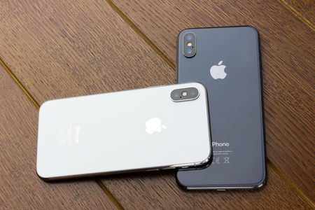 February 2018.Two Iphone X lies on a wooden table. A new smartphones from the company APPLE close-up on a wooden surface.のeditorial素材