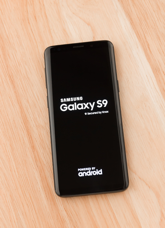 March 2018. Samsung Galaxy S9 is on the table. A new smartphone from the Samsung company lies on a wooden table close-up. The name of the gadget is displayed on the smartphone's display.のeditorial素材
