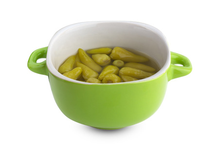 Marinated chili peppers on a white background. A few pickled chili peppers in a pottery dish against a white background.の写真素材