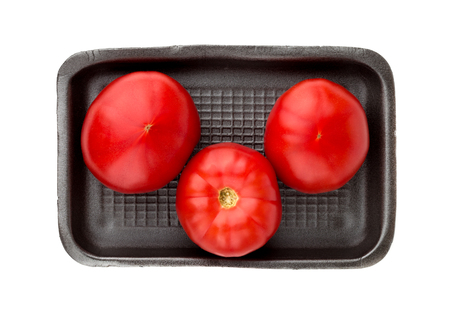 Tomatoes on a white background. Three fresh tomatoes in a plastic container from a supermarket.の写真素材