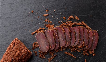 Cured meat on a slate board. Close-up of basturma sliced into pieces.の写真素材