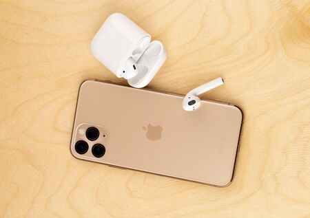 Rostov-on-Don, Russia - october 2019. Apple iPhone 11 Pro on a wooden surface. Apple's new smartphone close-up. Smartphone and AirPods earphones.のeditorial素材