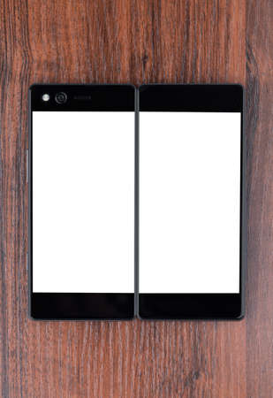 Smartphone with a blank white screen. New popular smartphone on a wooden surface.の写真素材