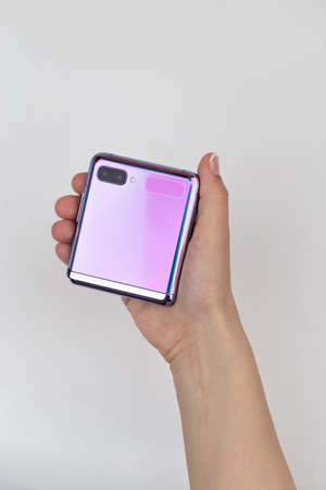 Rostov-on-Don, Russia - May 2021. Samsung Galaxy Z Flip on a gray background. New smartphone with a folding screen in hand on a gray background.のeditorial素材