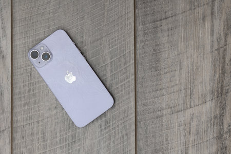 Shenzhen, China - September 2023. iPhone 15 with a broken back panel. Broken iPhone 15 close-up on a wooden background.のeditorial素材