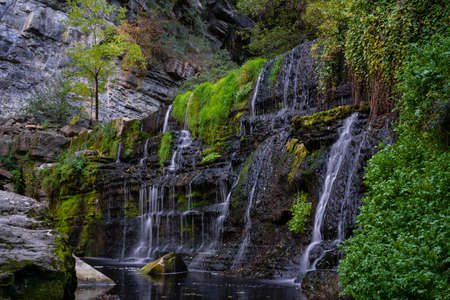 black stone wall with waterfalls falling between the forest and vegetation, rupit catalonia, spainの写真素材