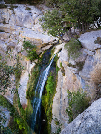 side view large waterfall between yellow rocks and vegetation, Salt de Sallent, rupit catalonia, spainの写真素材