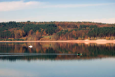 Lake Brombachsee in Autumn with reflection of forest in waterの写真素材