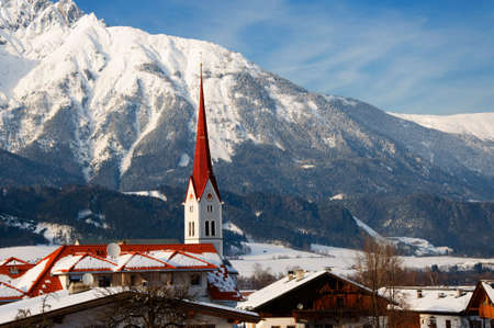 Church on snow-covered  mountains background in winter, Alps, Austriaの写真素材