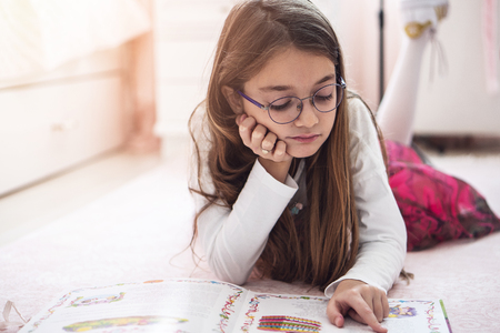 a child girl doing homework writing and reading at homeの写真素材
