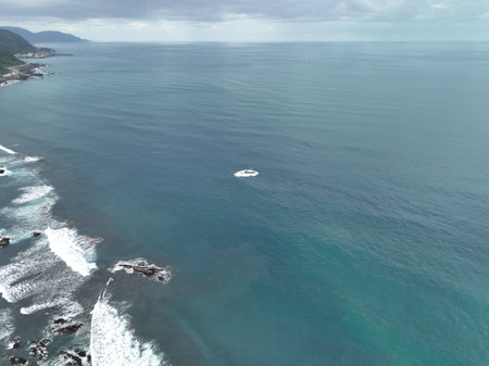 Aerial view of a boat in the sea and mountains in the background.