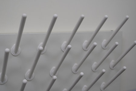Abstract close-up of a white laboratory pegboard drying rack.