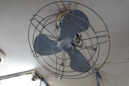 Closeup of a vintage electric fan on an old train ceiling.