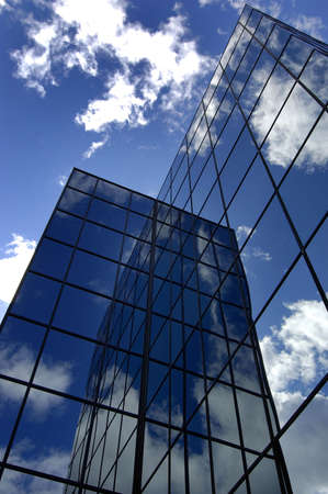 Office building reflecting sky and cloudsの写真素材