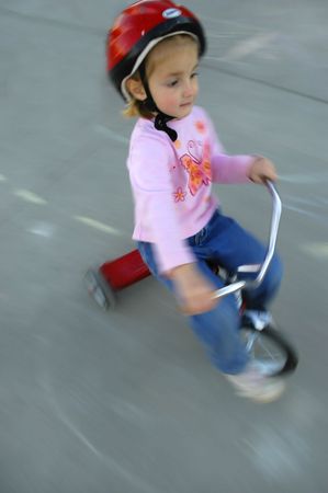 motion shot of little girl biking with red helmetの写真素材