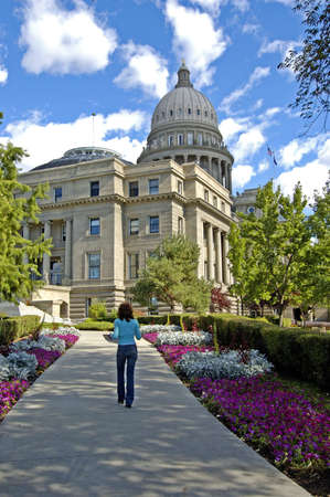 woman walking on sidewalk towards capital buildingの写真素材