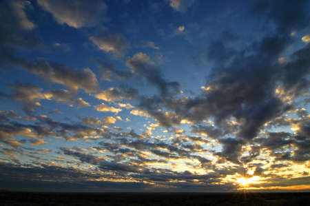 Early morning sunrise with sunburst and backlit cloudsの写真素材