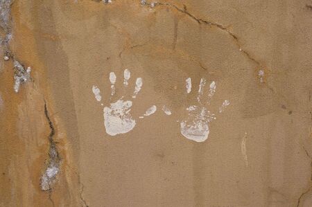 Detailed closeup of white handprints on textured cracked wallの写真素材