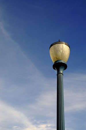 Detail of old light post with blue sky and clouds