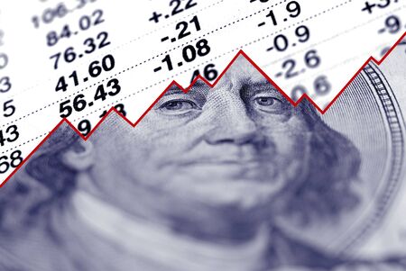 Closeup of hundred dollar bill with graph and stock chart in background