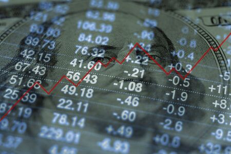 Closeup of hundred dollar bill with graph and stock chart in background